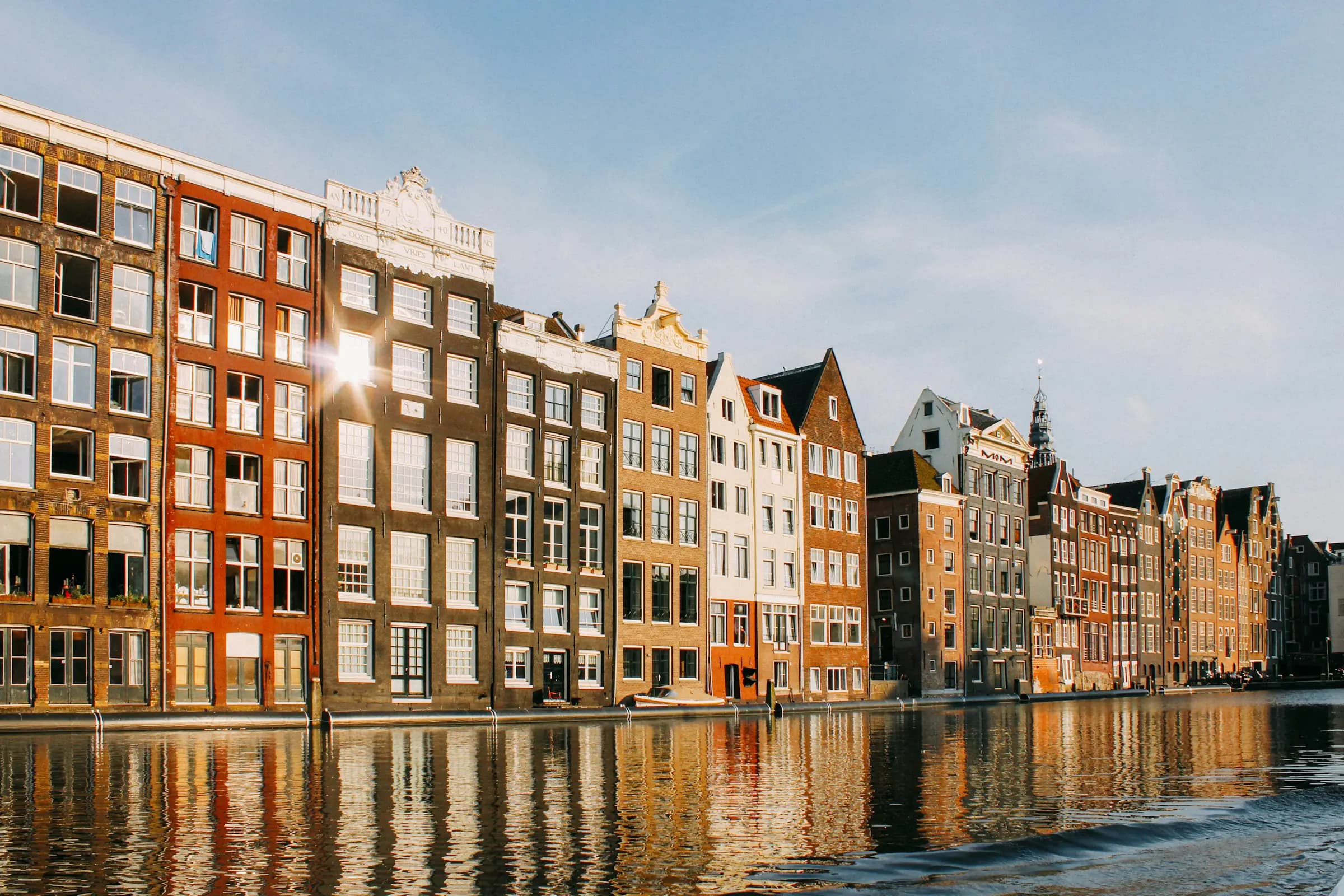 Amsterdamse grachtenpanden weerspiegelen in het kalme water bij laag zonlicht